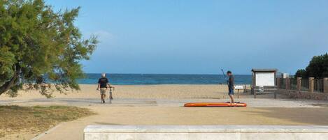 A beach with a concrete walkway, a signboard, and a lifeguard hut.
