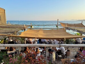 An outdoor dining area with tables and chairs, overlooking a body of water. - Juan-les-Pins, Antibes - 3-bedroom apartment near beaches and town center (Antibes)