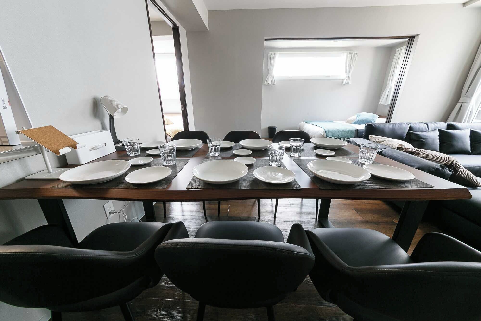 Een eetgedeelte met een houten tafel gedekt voor zes personen, omringd door zwarte stoelen.