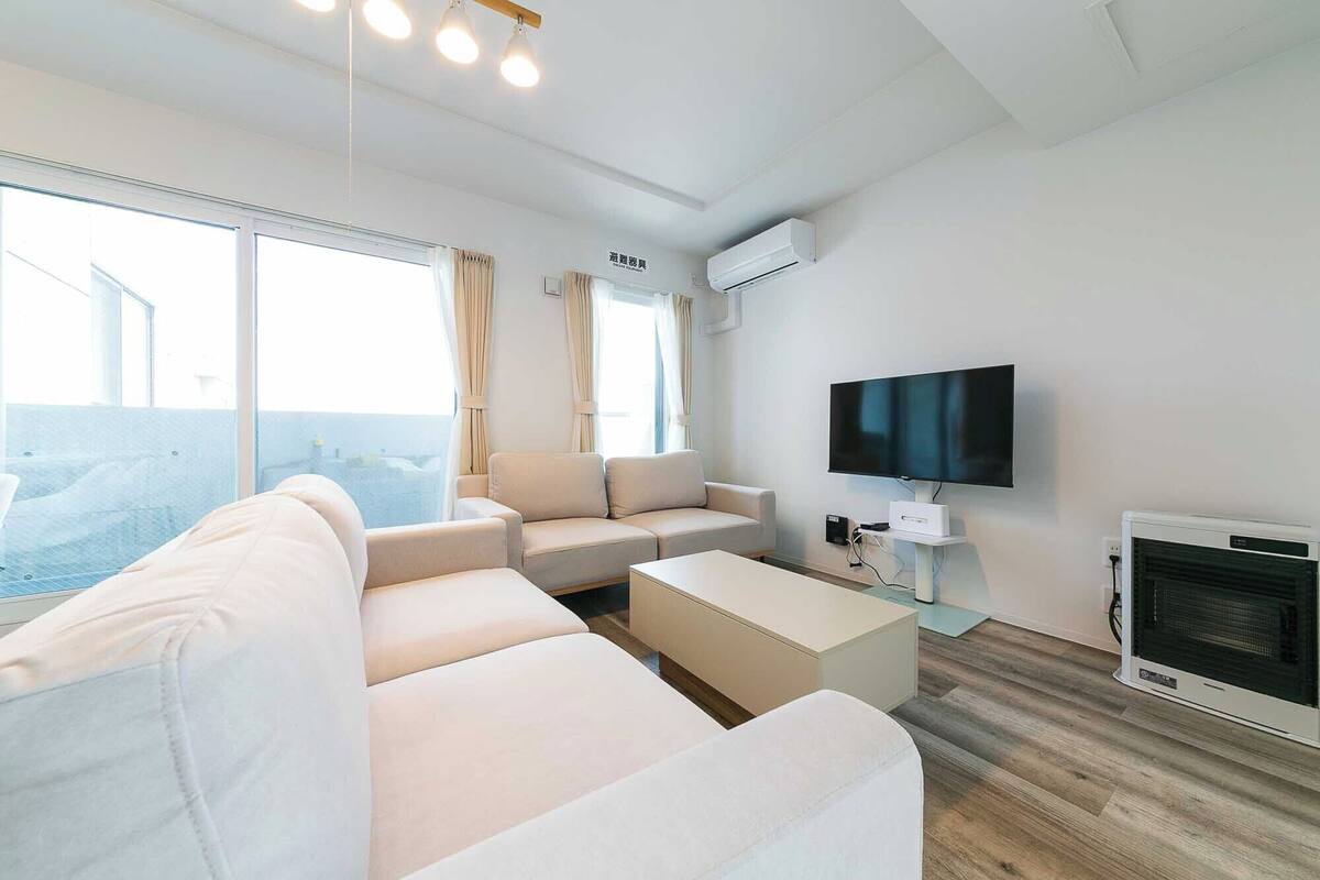 A modern living room with a sofa, a flat-screen TV, and a fireplace.