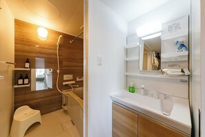 A modern bathroom with a wooden vanity, a mirror, and a shower area. - Twinberry CHITOSE (Chitose)
