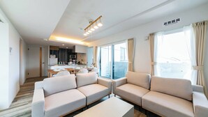 Una sala moderna con dos sofás, una mesita de centro y una cocina al fondo.
