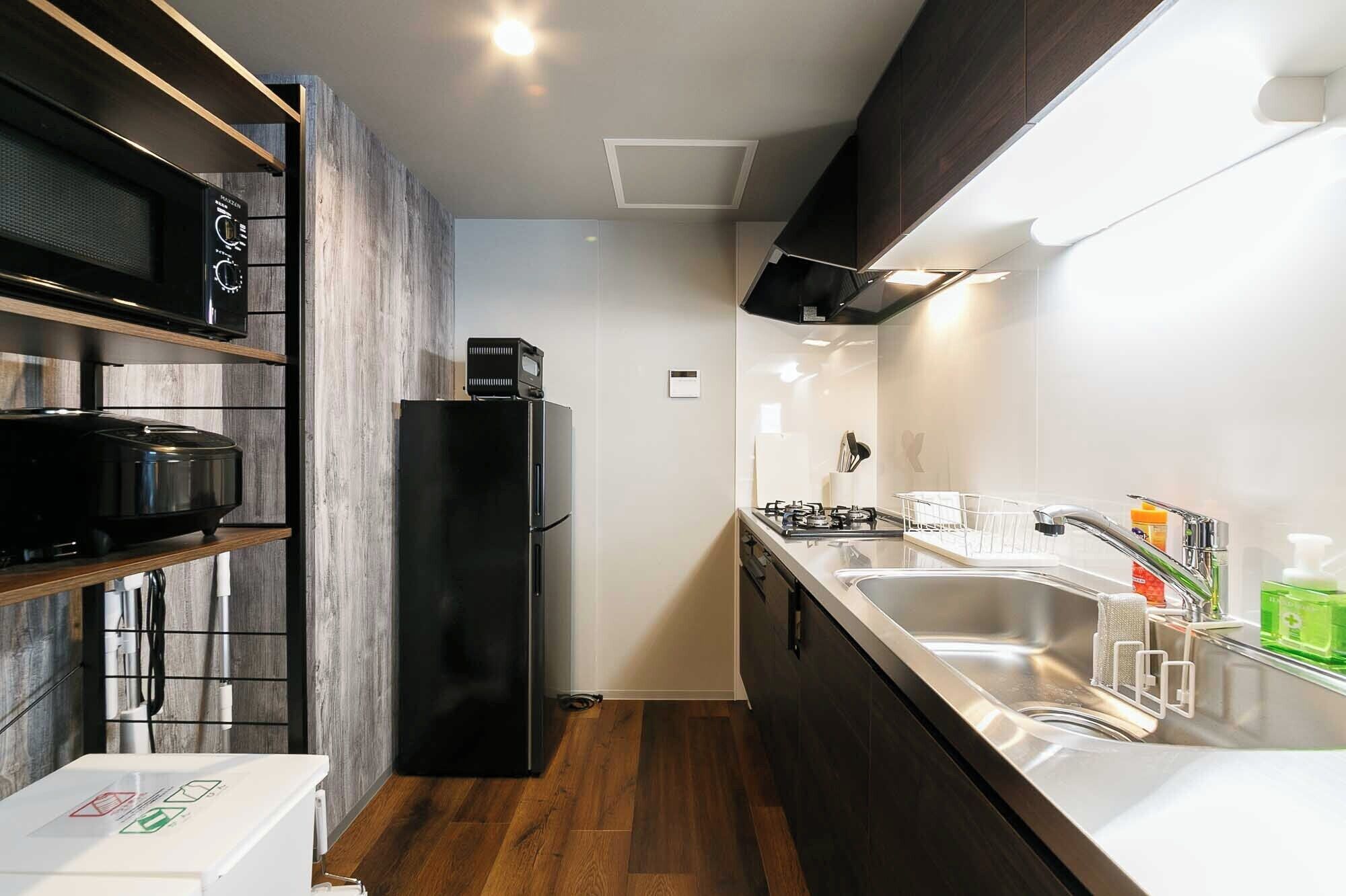 A compact kitchen with a microwave, refrigerator, stove, and sink.