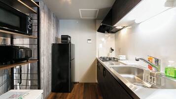A compact kitchen with a microwave, refrigerator, stove, and sink.