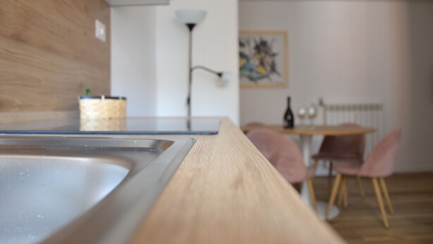 Une cuisine moderne dotée d’un plan de travail en bois, d’un évier et d’un coin repas avec des chaises et une table.