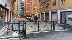 Un immeuble résidentiel à plusieurs étages doté de balcons, d’un magasin Sky Mobile et d’une entrée sécurisée avec un panneau indiquant « Passo Carrabile ».