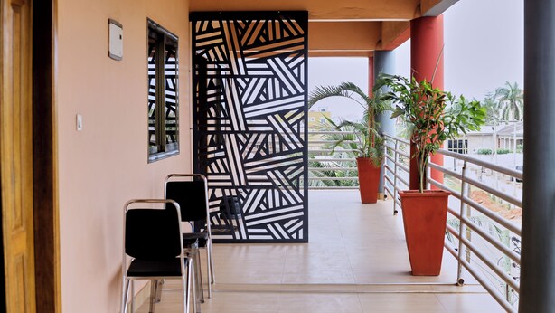 A balcony with chairs, a decorative partition, and potted plants. - Chic 1-bedroom apartment (Accra)