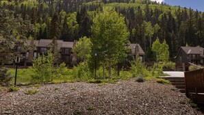 A residential area with houses, a forested hill in the background, and a gravel driveway. - Gorgeous Mountain Condo Near Purgatory Ski Resort (Durango)