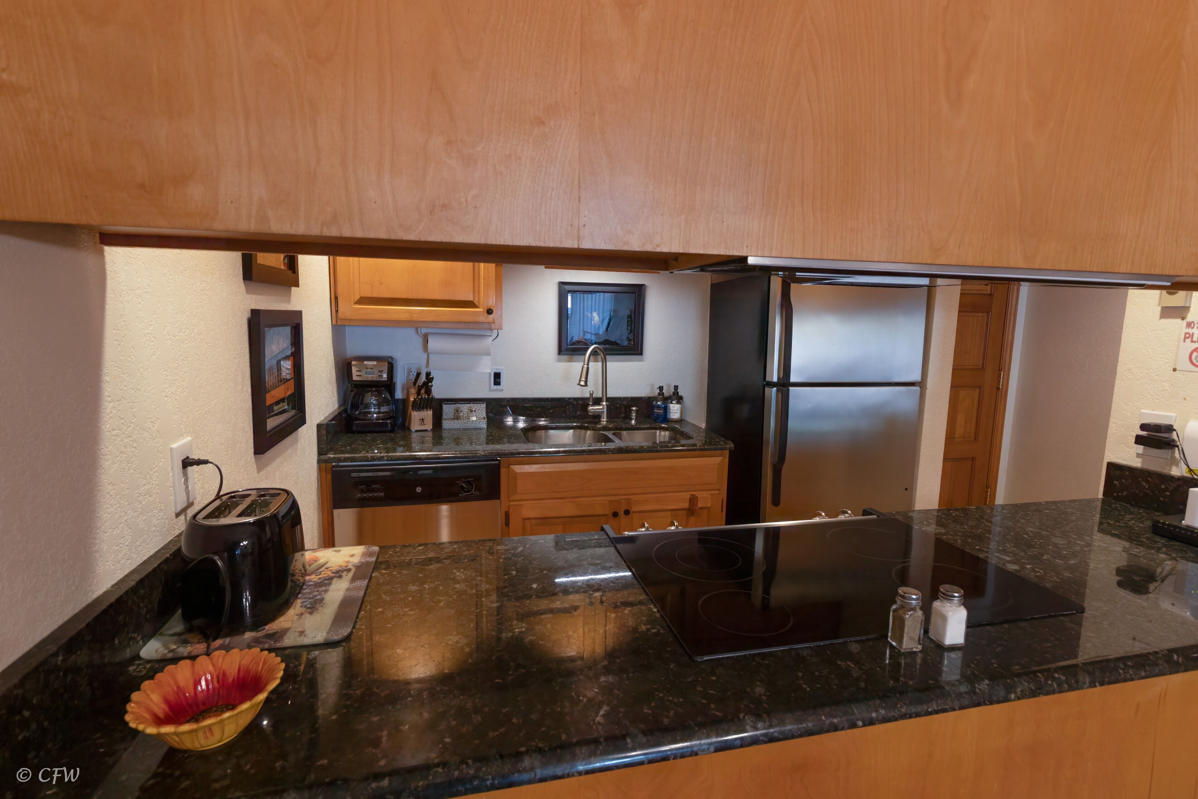 A kitchen with wooden cabinets, a stainless steel refrigerator, a toaster, and a microwave.