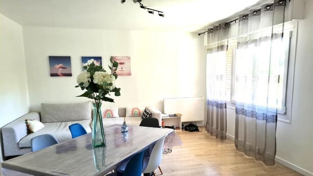 A modern living room with a dining area, featuring a sofa, chairs, a glass-top table, and a vase with flowers. - In the Clouds - Free parking -Independent entrance (Mulhouse)