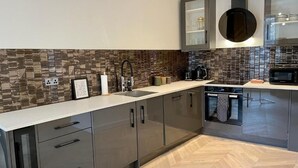 A modern kitchen with a herringbone wood floor, stainless steel appliances, and a herringbone tile backsplash. - NEW LISTING Perfect City Location, renovated, comfortable, iconic views (Edinburgh)