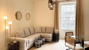 A modern living room with a sectional sofa, a glass dining table, and a large window with curtains. - NEW LISTING Perfect City Location, renovated, comfortable, iconic views (Edinburgh)