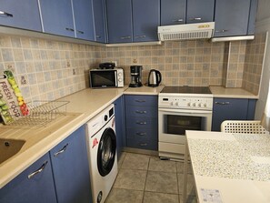 Una cocina compacta con lavadora, microondas, cocina y cafetera.