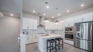 A modern kitchen with white cabinetry, stainless steel appliances, and pendant lighting. - All the Florida fun you can have in this charming 3-bedroom townhome in downtow (Sarasota)