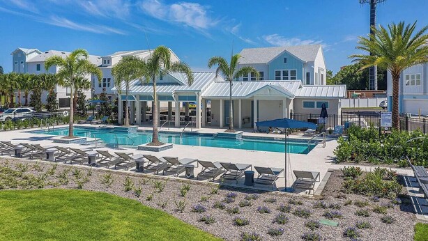 A pool area with lounge chairs and palm trees. - All the Florida fun you can have in this charming 3-bedroom townhome in downtow (Sarasota)