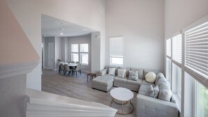 A spacious living area with a sectional sofa, a round coffee table, and a dining area with a table and chairs. - All the Florida fun you can have in this charming 3-bedroom townhome in downtow (Sarasota)