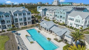 A residential complex with a swimming pool, multiple houses, and a city skyline in the background. - All the Florida fun you can have in this charming 3-bedroom townhome in downtow (Sarasota)
