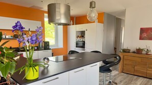 A modern kitchen with a central island, white cabinets, and a hanging light fixture. - Les Sylphides (Pruzilly)
