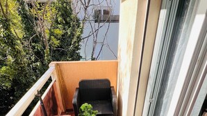 A balcony with wicker furniture, a small table with a plant, and a sliding glass door. - Apartment with 2 large bedrooms (Montpellier)
