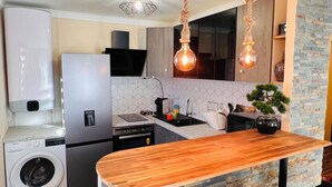 A modern kitchen with a central island, a built-in washing machine, and a dining area with black chairs. - Apartment with 2 large bedrooms (Montpellier)