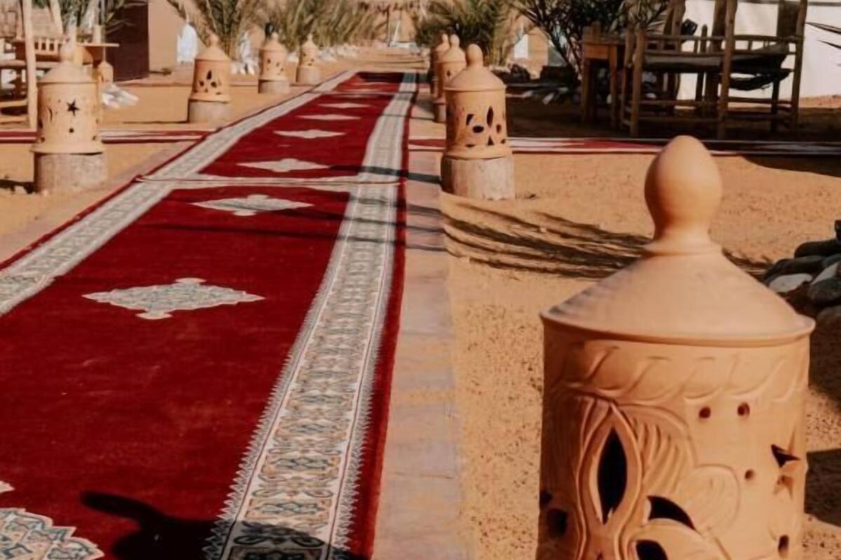 A corridor with a red carpet leading to a building with a desert backdrop.