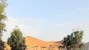 Paisatge desert amb una catifa vermella que condueix a un edifici. Hi ha làpiades i un senyal amb la inscripció "HAJUN".