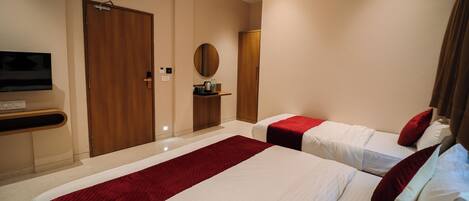 A hotel room with two beds, a TV, a mirror, and a wardrobe.