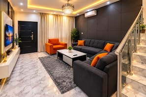 A modern living room with a sofa, a coffee table, and a TV. - Charming 3-bedroom ocean view estate with WiFi, AC in adorable Kokrobite (Kokrobite)