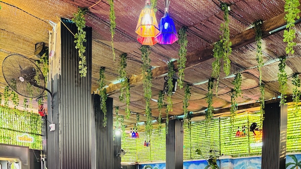 Un área de piscina interior con tumbonas de madera, una piscina pequeña y plantas colgantes.