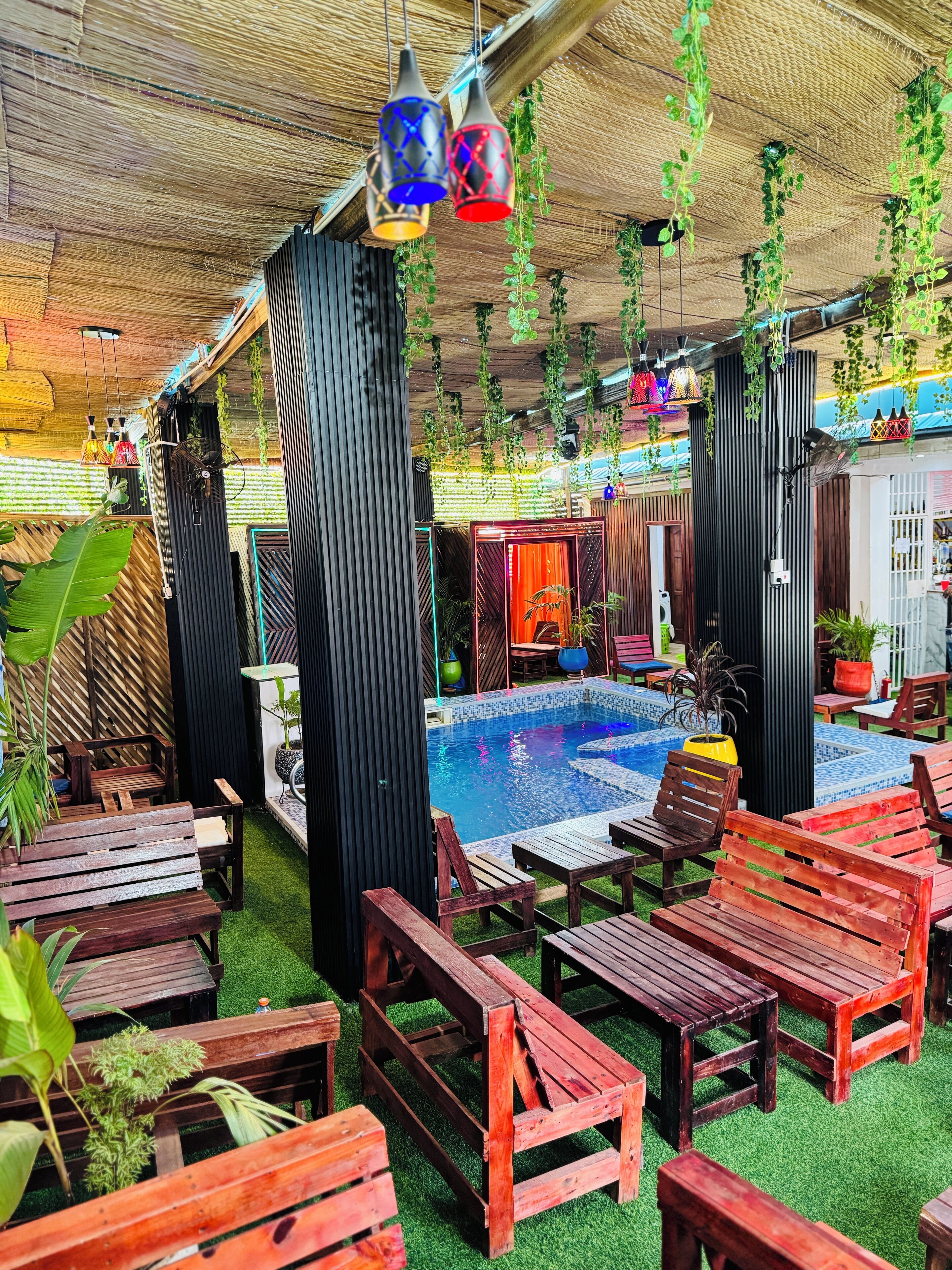 An outdoor pool area with wooden furniture and hanging plants.