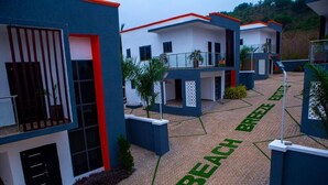 Un edificio moderno con una combinación de colores azul y blanco, que presenta un área pavimentada con la inscripción