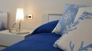 Un dormitorio con cama, mesita de noche, lámpara e interruptor de luz en la pared.
