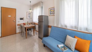 A compact living space with a kitchenette, a dining area, and a sofa with cushions.