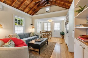 A spacious living room with a high ceiling, a dining area, and a bookshelf.