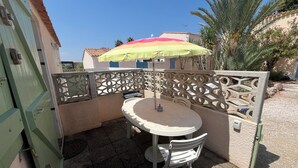 Una terrazza esterna con tavolo e sedie, un recinto decorativo e un ombrello colorato.