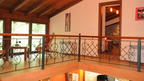 A wooden balcony with wrought iron railings, a stone wall, and a painting on the wall.