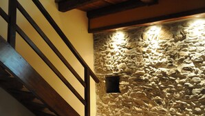 A staircase with wooden beams and a stone wall with a small window.