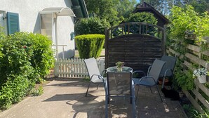 A patio with a table and chairs, a wooden gate, and a hedge. - Cozy vacation apartment in a quiet location on the Prerower Strom (Prerow)