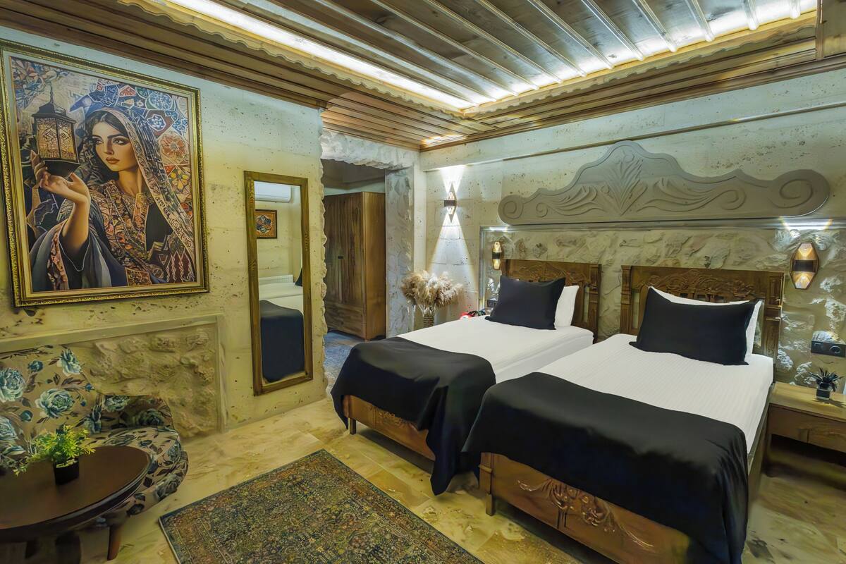 A room with two beds, a large painting, a mirror, and a decorative rug.