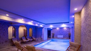 Un espace de bien-être avec une piscine, des murs en pierre et des chaises longues.