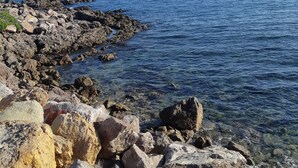 A rocky shoreline with clear blue water and a distant horizon. - Exceptional view of the sea from the popular Corniche district (Sète)