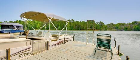 A wooden dock with a covered boat named 'CRES' and a green metal chair.