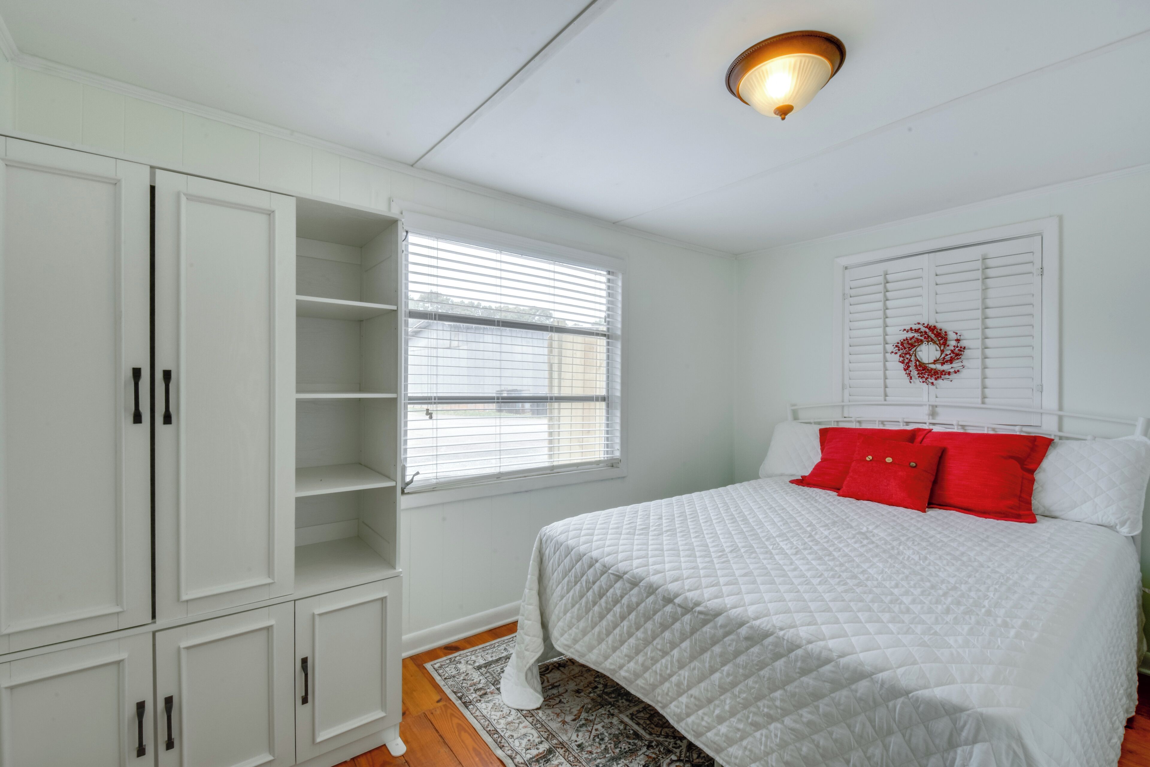 Un dormitorio con cama, armario blanco y ventana con persianas.