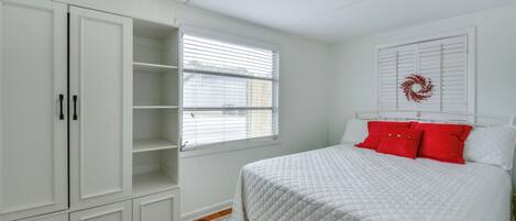 Un dormitorio con cama, armario blanco y ventana con persianas.