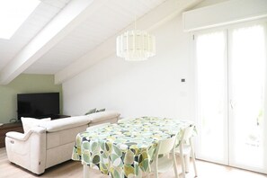 Una sala moderna con un sofá, una mesa de comedor y un televisor.