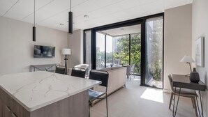Een moderne keuken met een marmeren aanrechtblad, zwarte stoelen en een groot raam met uitzicht op de omgeving.