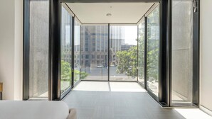 Een moderne hotelkamer met grote ramen van de vloer tot aan het plafond, een minimalistisch design en uitzicht over de stad.