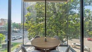 Een moderne kamer met een groot raam en uitzicht op een straat met bomen.