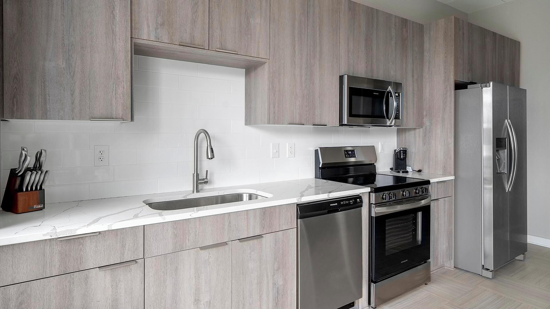 A modern kitchen with a stainless steel refrigerator, microwave, stove, and dishwasher.