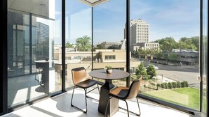 Una habitación moderna con ventanas amplias, dos sillones de cuero, una mesa redonda y una planta en maceta.